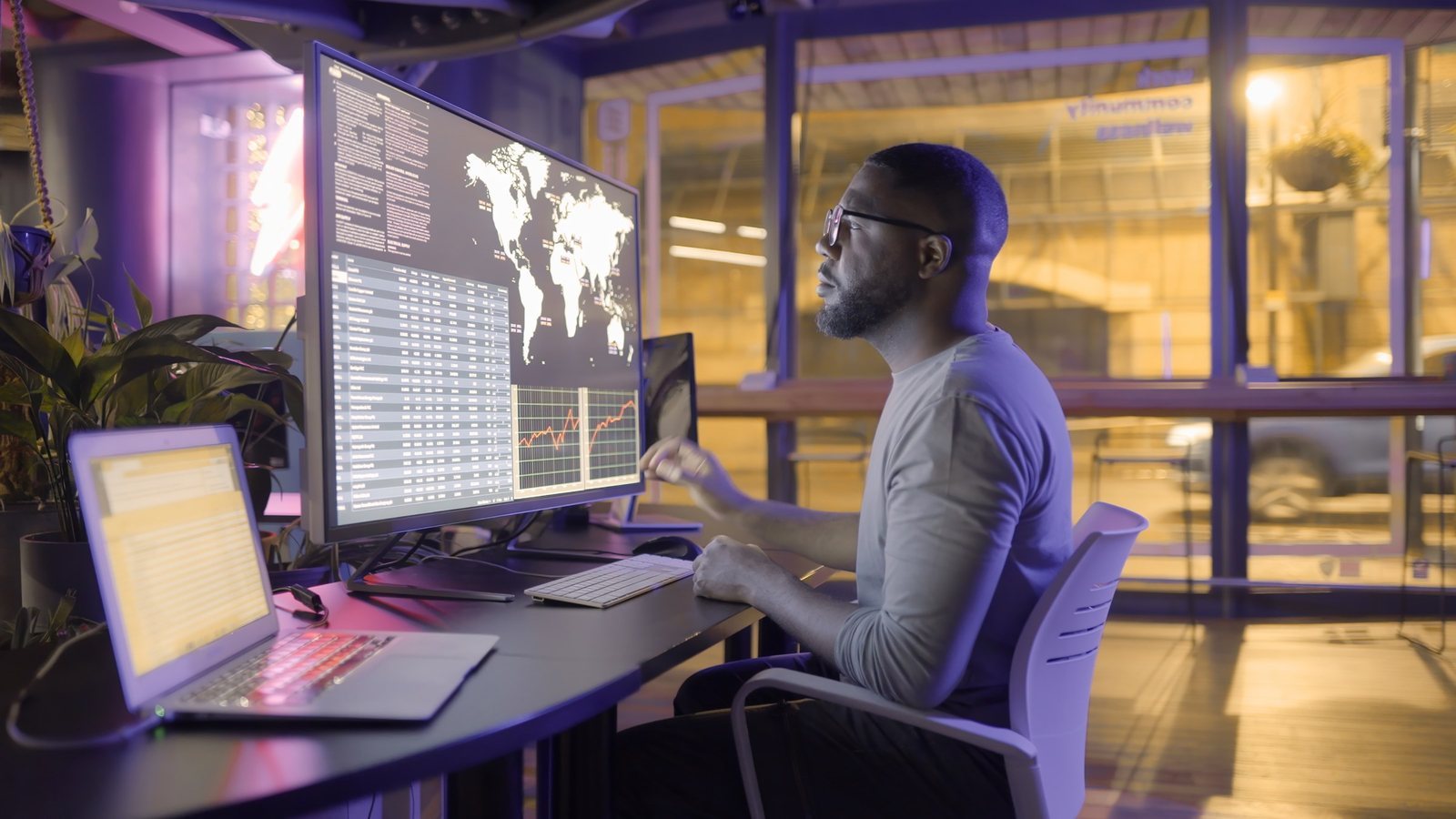 An engineer monitoring global transaction data across screens at night