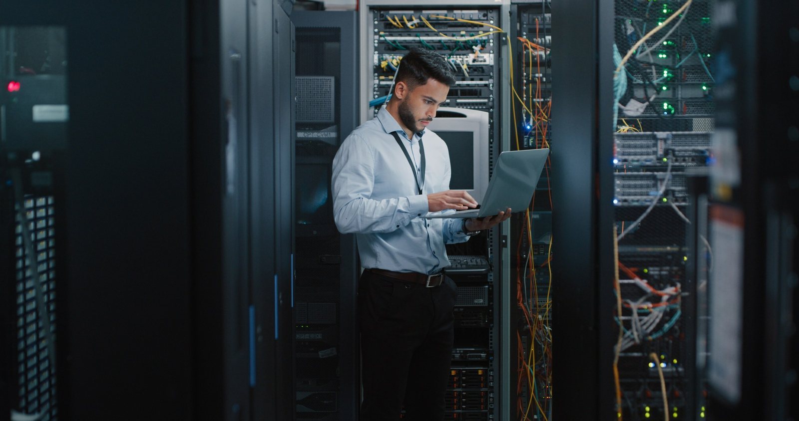 An infrastructure engineer working on a laptop in a server room