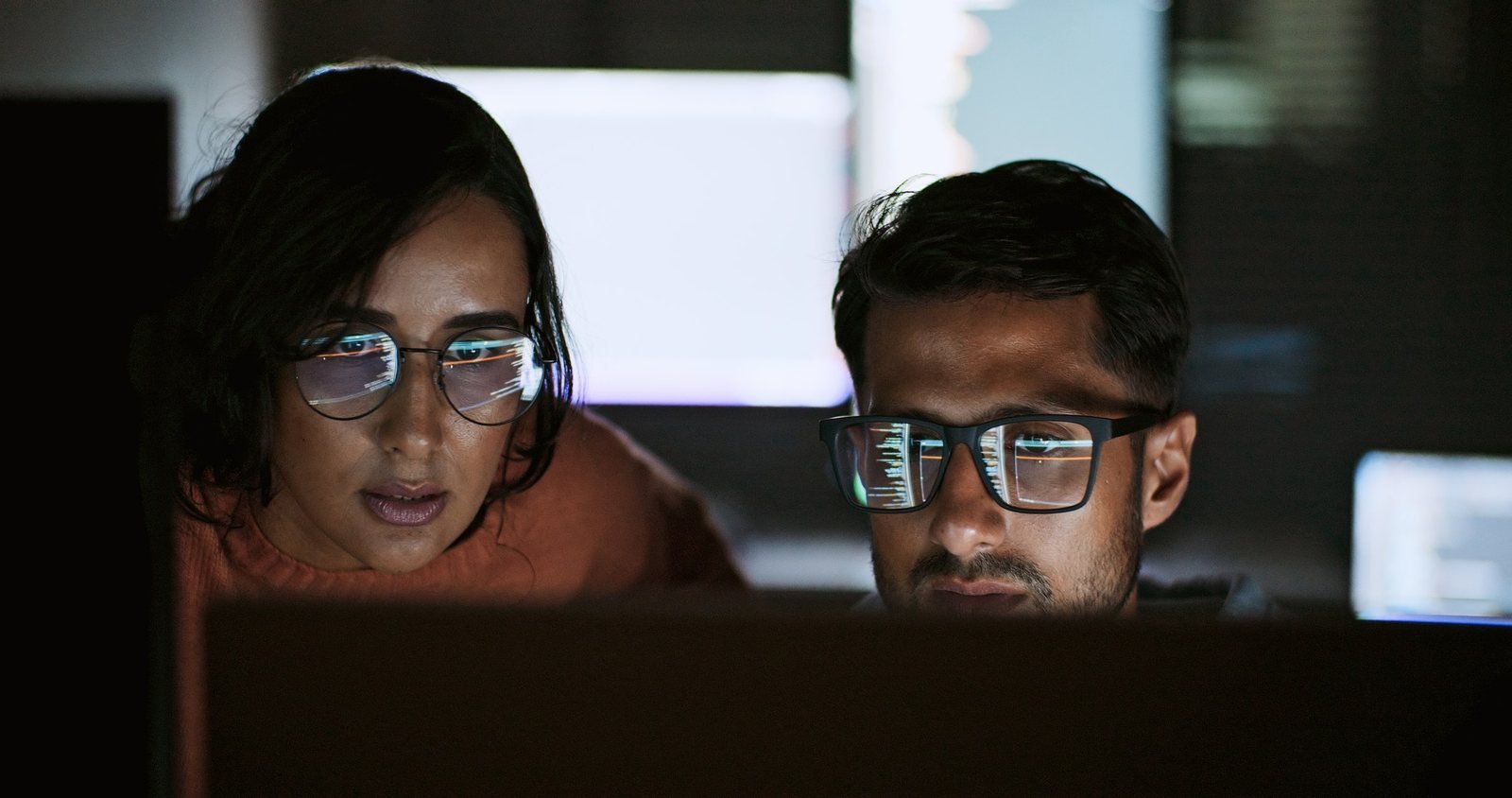 Two software engineers reviewing code together late at night